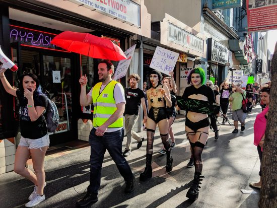 Bryan and Lexi Lore, holding the "Sex Work Is Real Work" sign, march for International Whores Day. Photo: Jux Lii